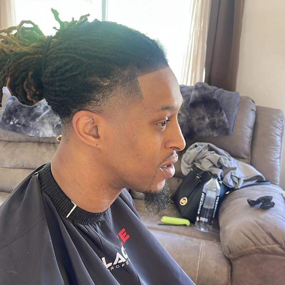 Side view of a low fade with waves, pulled-back locs and a crisp temple line by Jeremiah Lomax