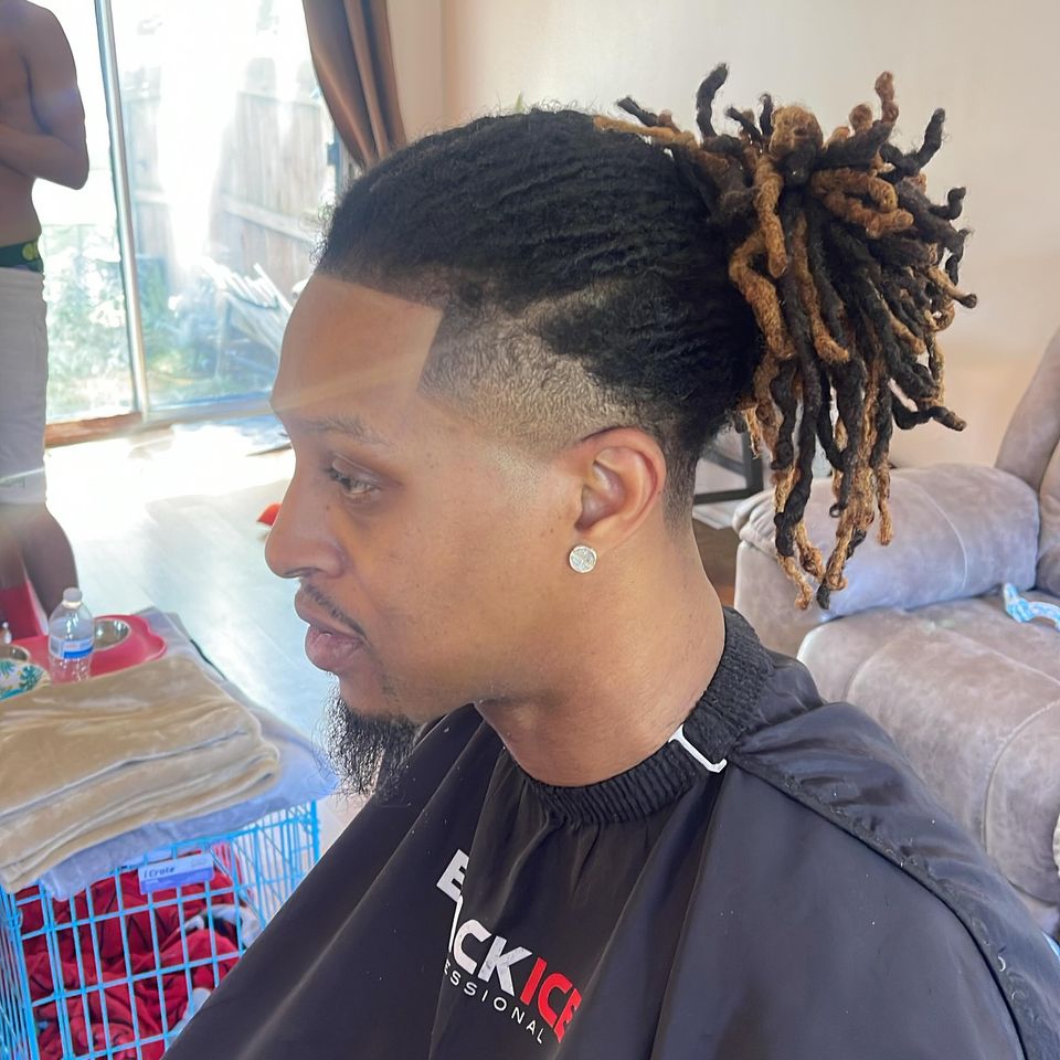 Barber Jeremiah Lomax’s work: a low fade with a sharp line-up, defined waves and long two-tone locs pulled back
